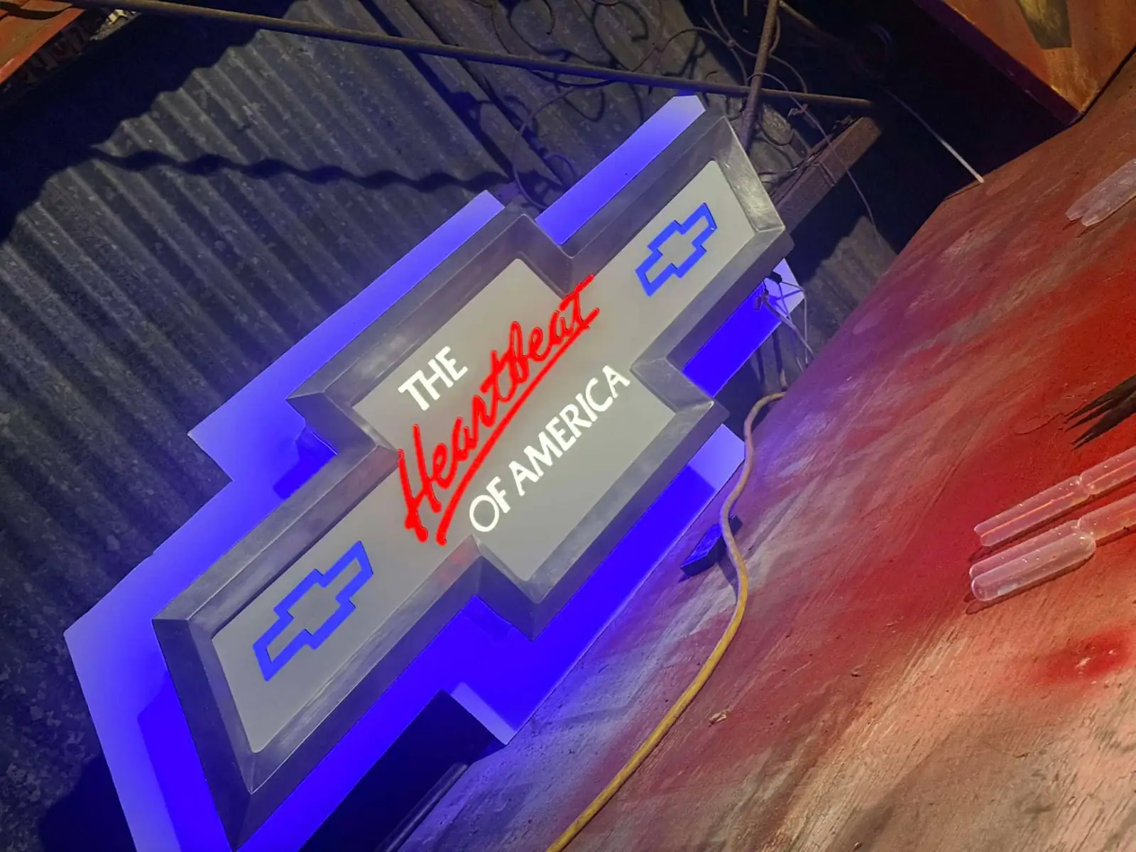 Backlit heartbeat-of-america bowtie sign glowing blue against a metal shop wall in Louisiana