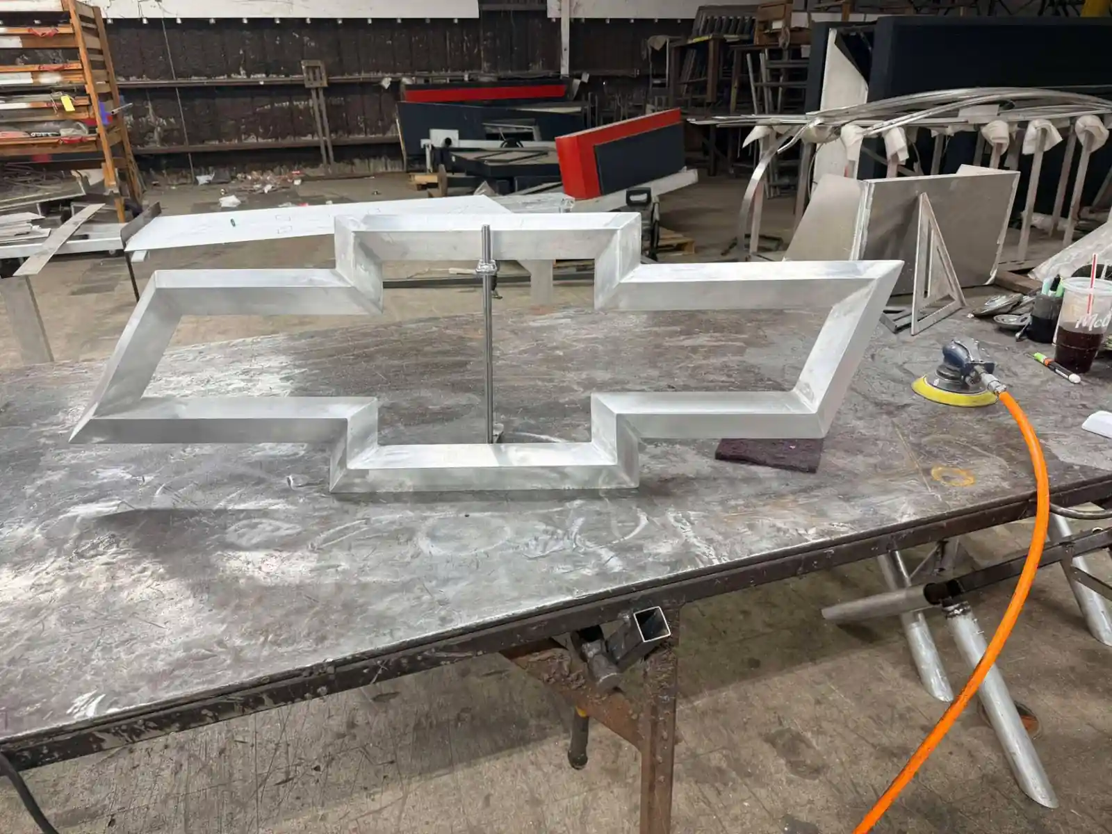 Bare aluminum bowtie channel letter shell clamped for finish sanding in Avoyelles Parish, Louisiana