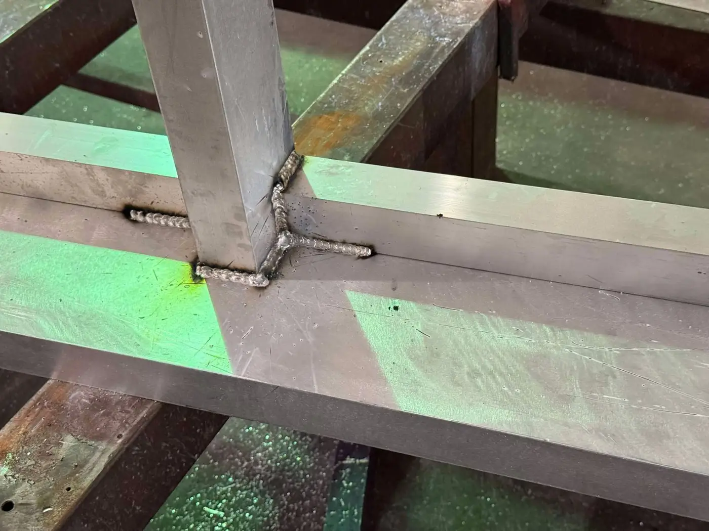 Close-up of a stacked aluminum weld bead joining an upright to the rail of a sign support frame in the Bunkie shop