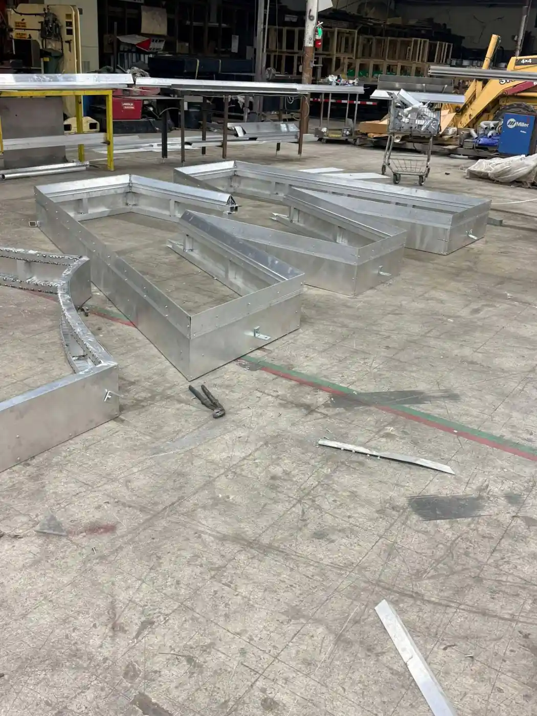 Oversized aluminum channel letter pans laid out across the shop floor before finishing in Bunkie