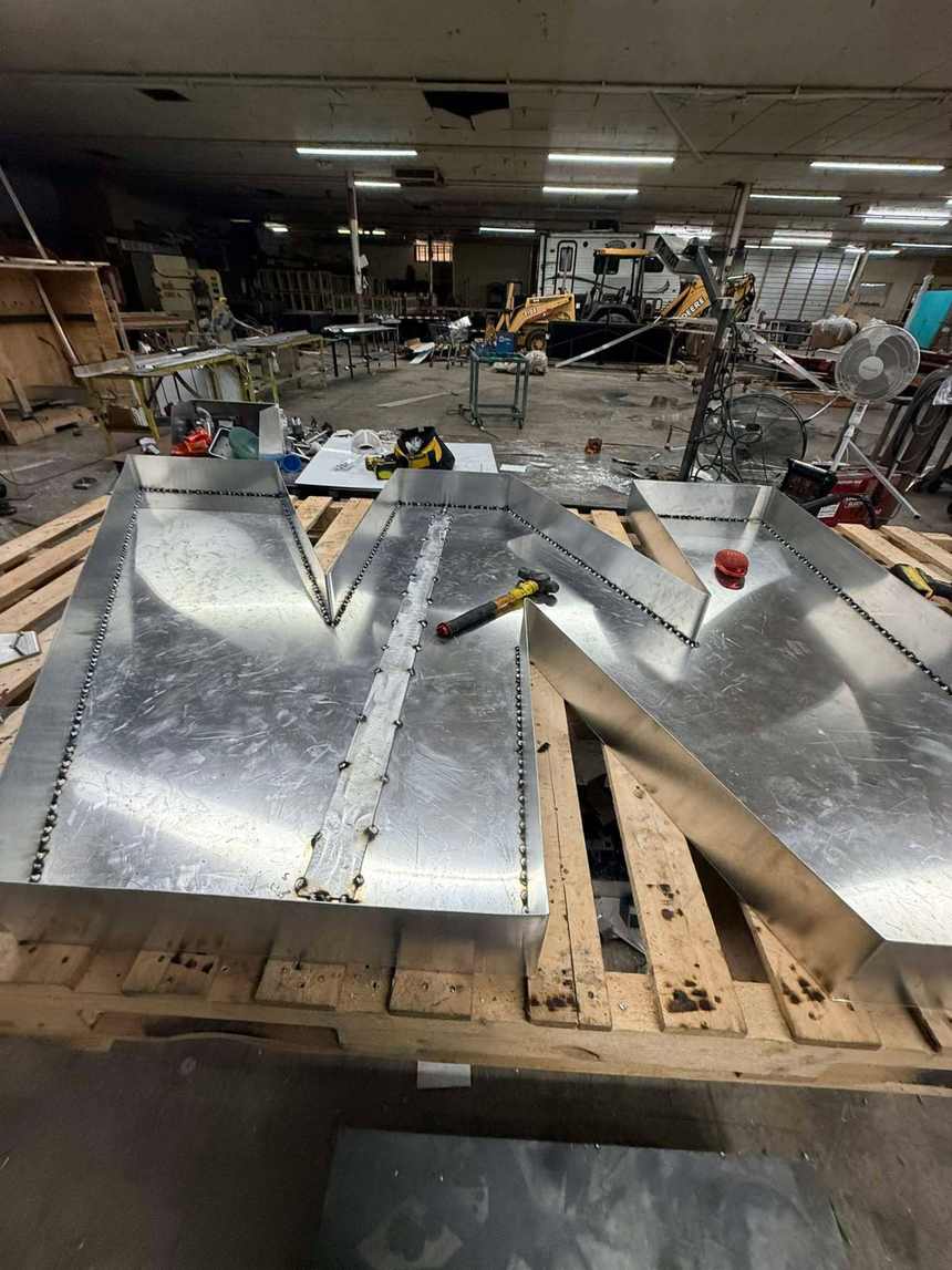 Custom aluminum channel letters laid out on pallets during fabrication in Bunkie, Louisiana
