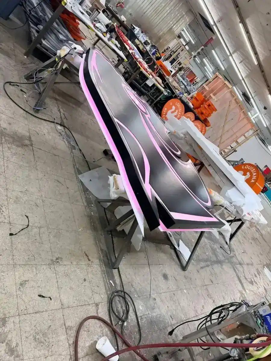 Halo-lit dimensional channel letter sign glowing pink on the bench during a lighting test in the shop