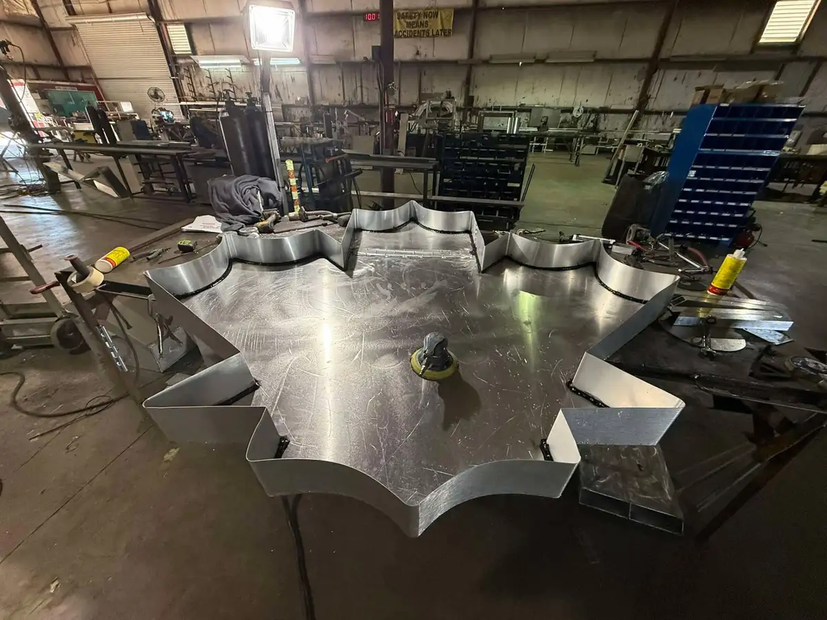 Large formed aluminum star sign pan with curved returns tacked around the face on the shop bench