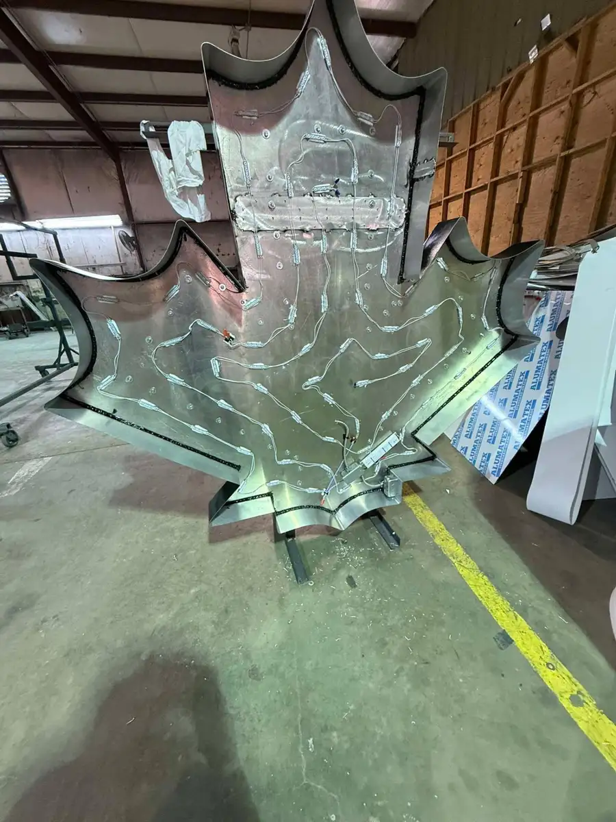 Back of an oversized aluminum maple leaf sign pan with LED modules and wiring laid out before the face goes on