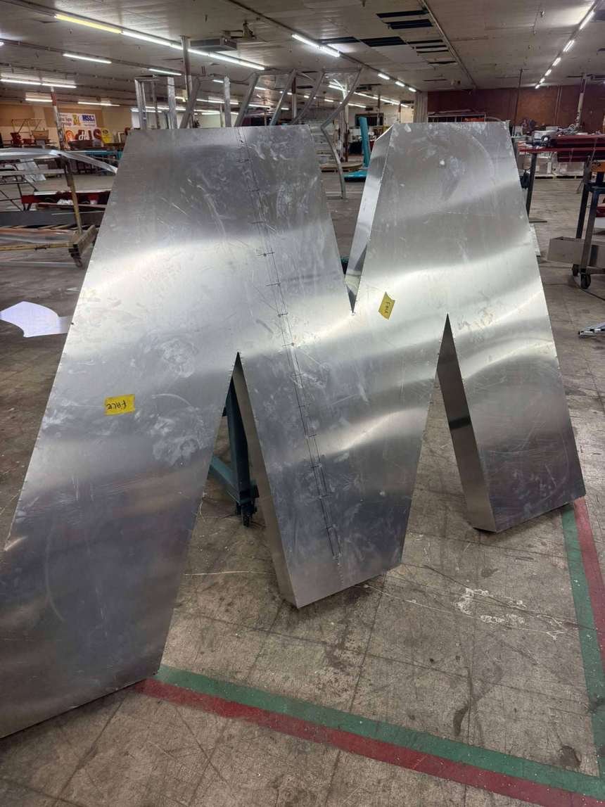Large aluminum sign letter M standing in the fabrication shop in Louisiana