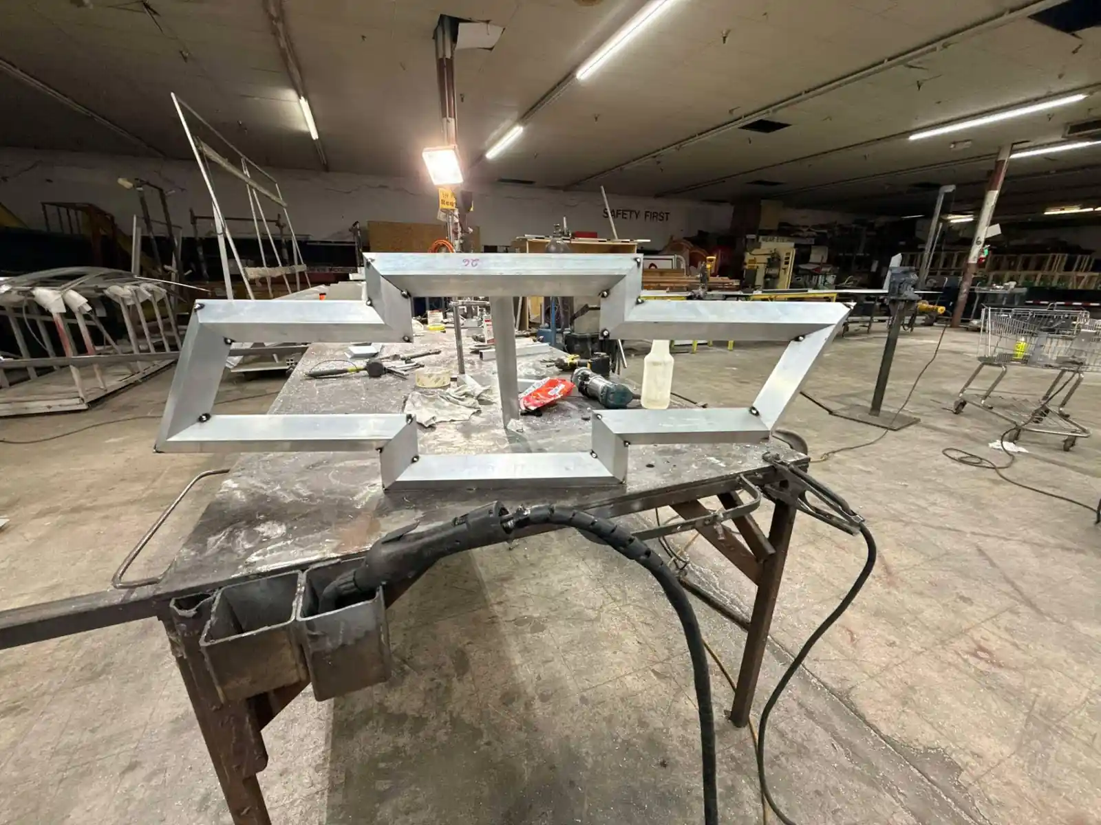 Welded aluminum bowtie sign frame set up on a welding table in the Bunkie fabrication shop