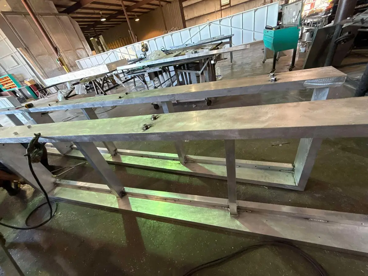 Two long welded aluminum sign support frames staged across the fabrication shop floor in Bunkie, Louisiana