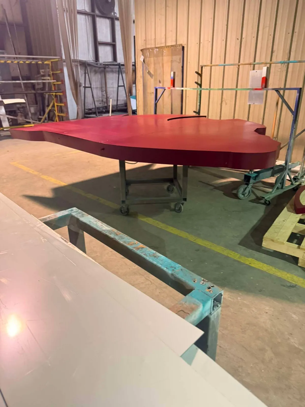 Large dimensional sign panel finished in red paint on a rolling cart during the finishing stage